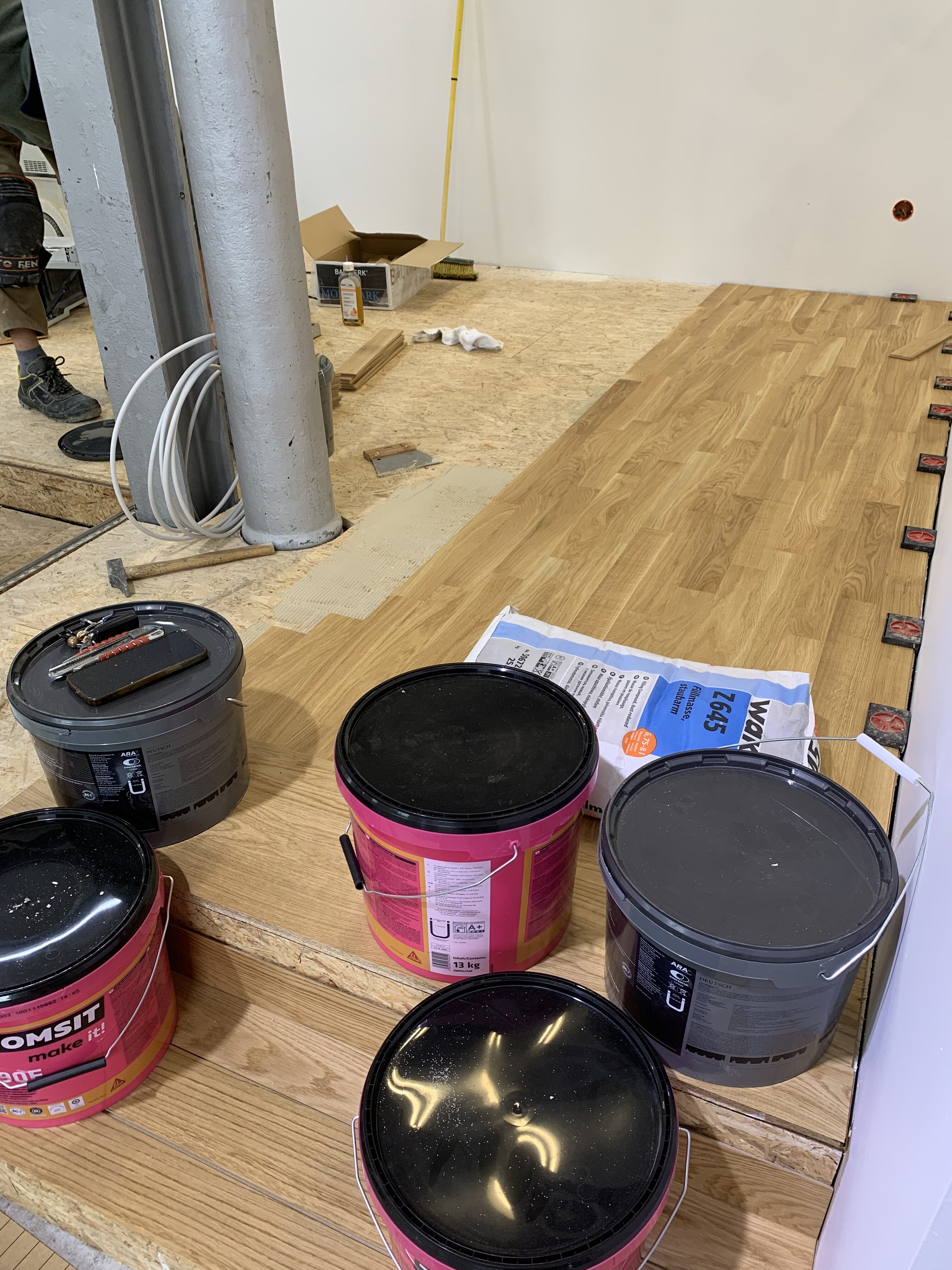 Holzdeck während der Parkettlege Arbeiten, im Vordergrund stehen Eimer mit Kleber